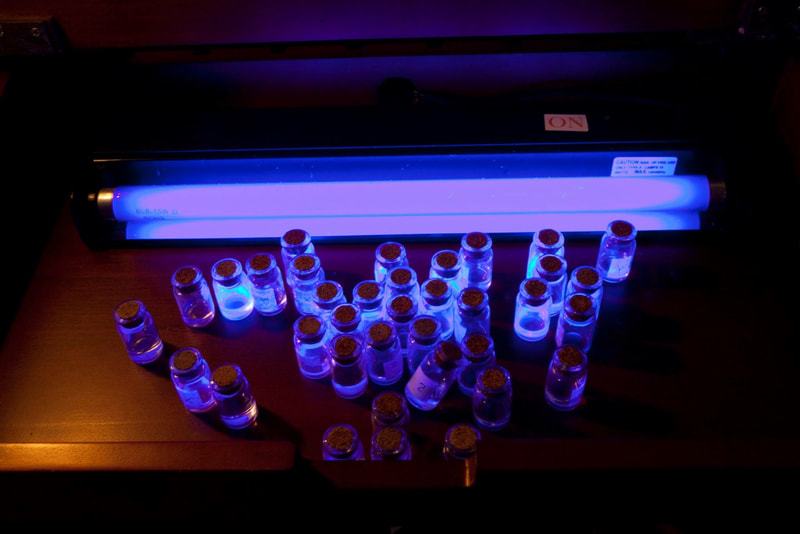 Vials of liquid glowing under UV light.